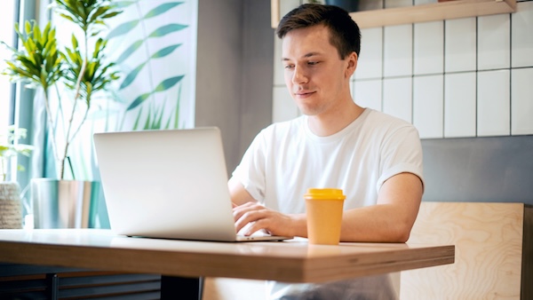 Man uses laptop at a cafe
