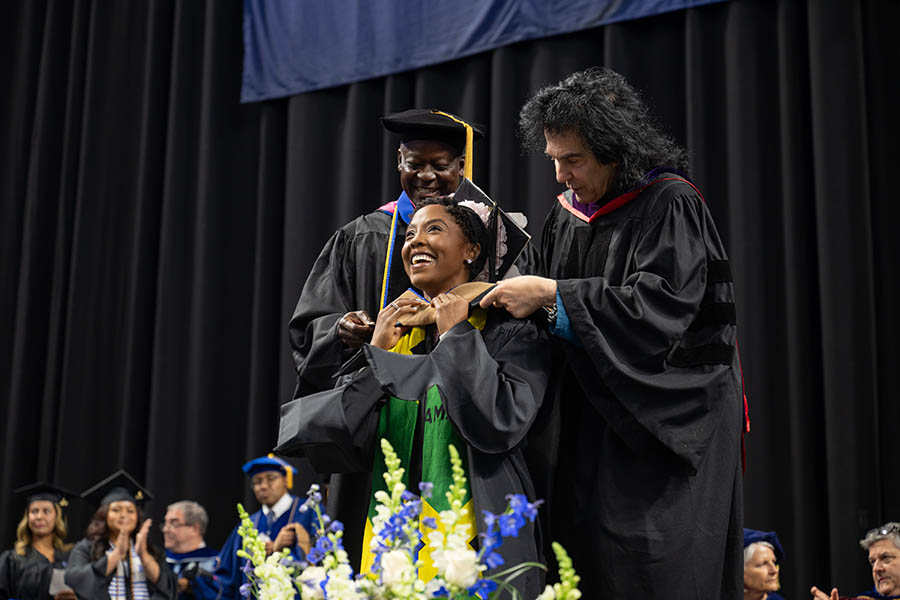 A student in cap and gown at her graduation ceremony being congratulated
