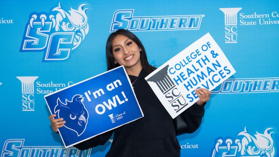 Woman holding signs, one saying I'm an Owl, the other saying College of Health and Human Services